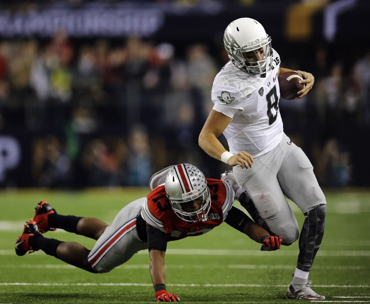 Oregon's Marcus Mariota (8) runs past Ohio State's Eli Apple (13) during the first half of the NCAA college football playoff championship game Monday, Jan. 12, 2015, in Arlington, Texas.
