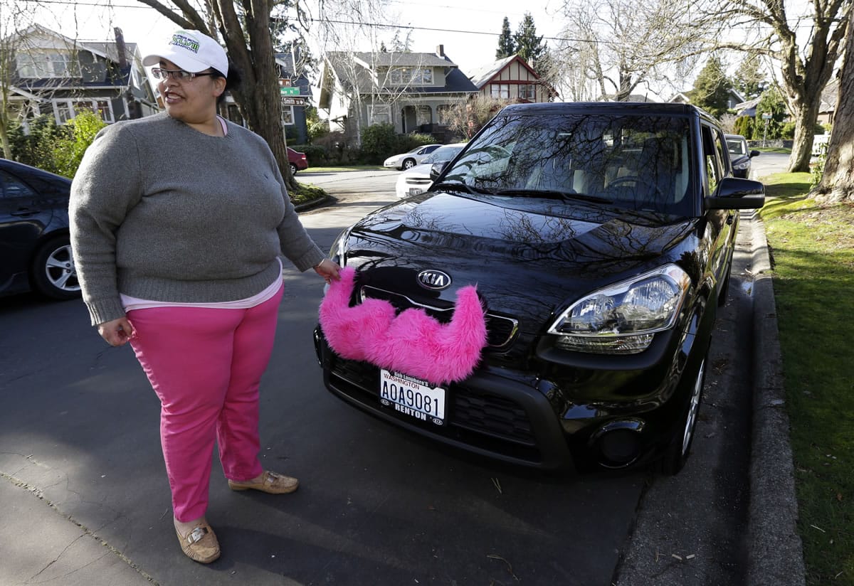 Driver Dara Jenkins adjusts the furry mustache Lyft drivers display on their cars when they are working, as she starts a shift in Seattle.