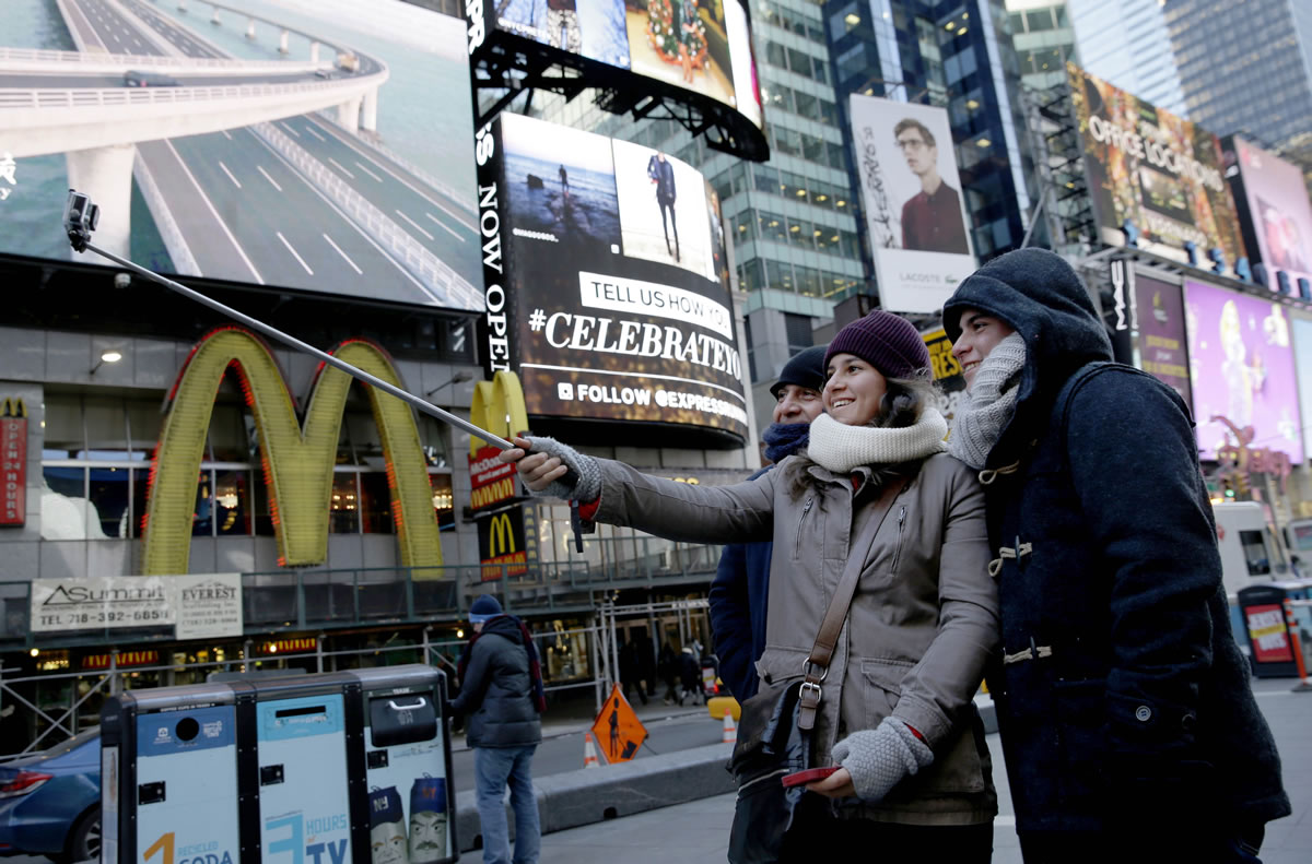 Cristina Gutierrez, center, takes a picture Thursday of herself, her brother, Hector Gutierrez Jr., right, and her father, Hector Gutierrez Sr., using a selfie stick in Times Square in New York.