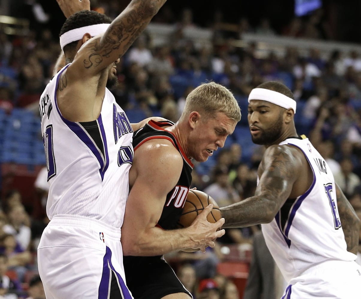 Portland Trail Blazers center Mason Plumlee, center, tries to drive between Sacramento Kings' Willie Cauley-Stein, left, and DeMarcus Cousins during the first quarter of an NBA preseason game in Sacramento, Calif., Saturday, Oct. 10, 2015.