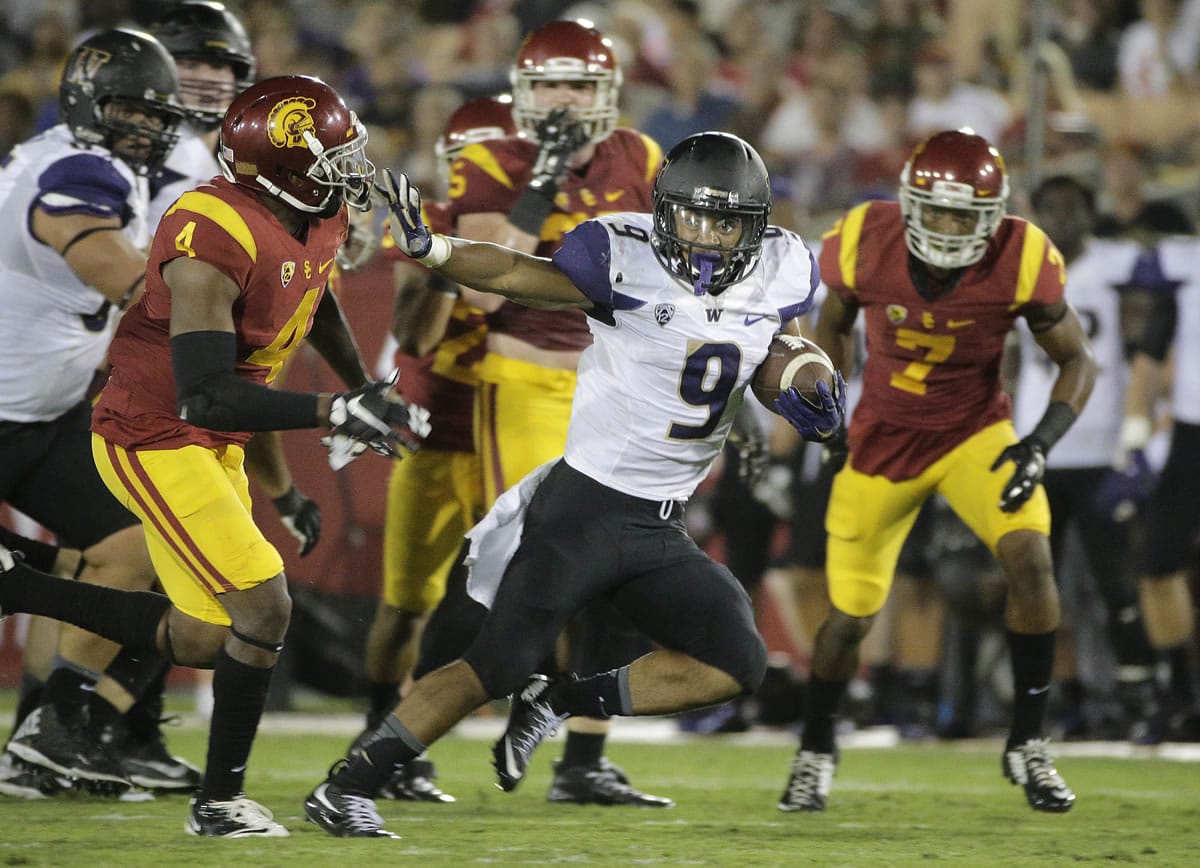 Washington's Myles Gaskin, center, carries the ball under pressure by Southern California's Chris Hawkins, left, during the second half on Thursday, Oct. 8, 2015, in Los Angeles. Washington won 17-12. (AP Photo/Jae C.