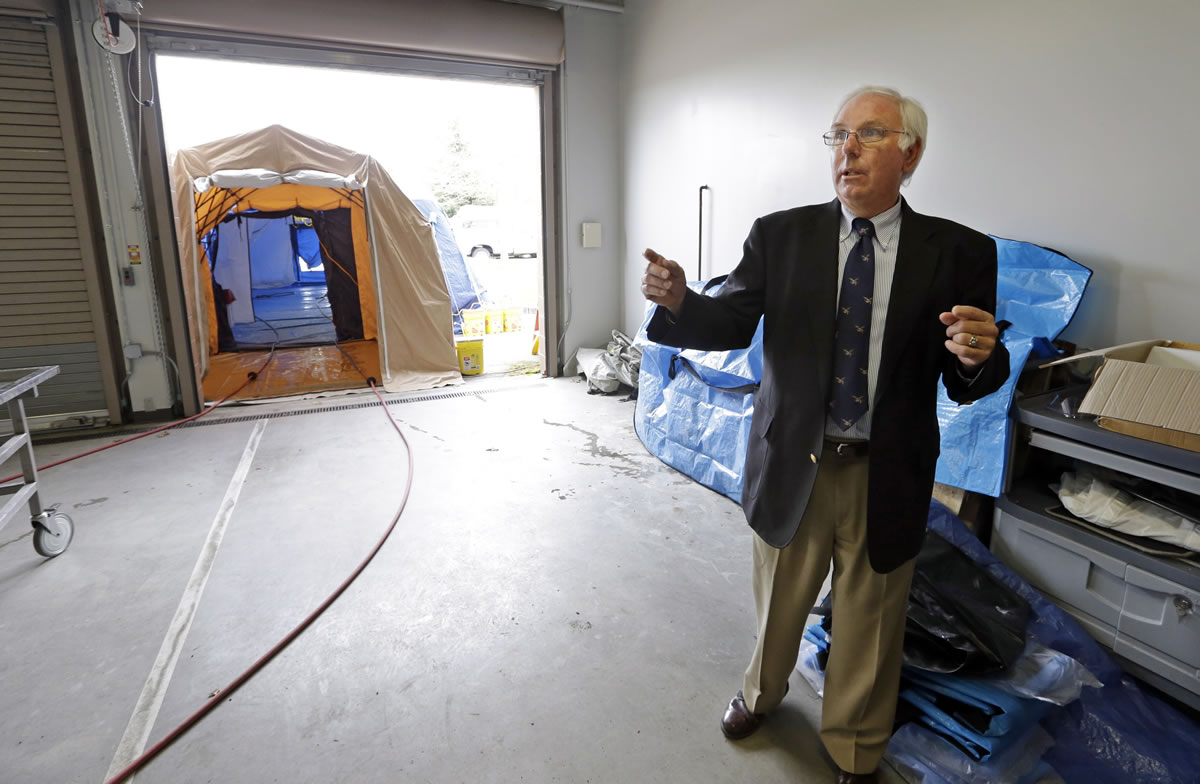 Dennis Peterson, Snohomish County Medical Examiner's office deputy director, talks Wednesday in Everett about the tented area behind him, which is used for decontaminating bodies recovered after the March 22 mudslide at Oso.
