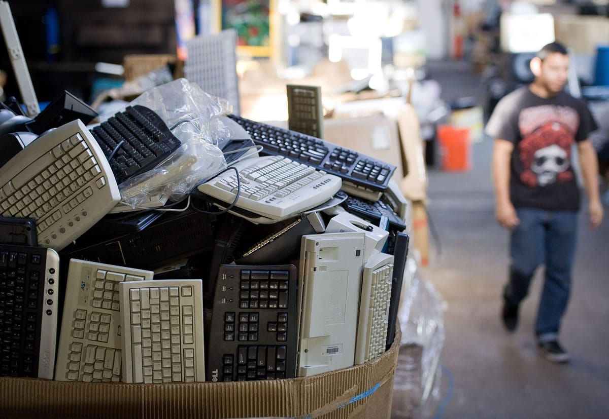 Employee Diego Cuellar walks by a box of old computer keyboards in the EZPC warehouse in Santa Ana, Calif.