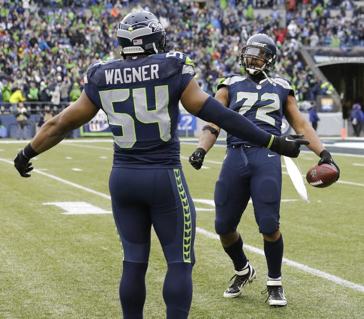 Seattle Seahawks defensive end Michael Bennett, right, celebrates after recovering a fumble, with middle linebacker Bobby Wagner during the first half of an NFC divisional playoff NFL football game against the New Orleans Saints in Seattle, Saturday, Jan. 11, 2014.