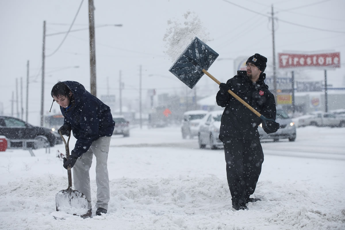 Vincente Echeverria, left, and Glen Harrison clear the driveway leading to the Salvation Army store on Highway 99 in Vancouver on Saturday.