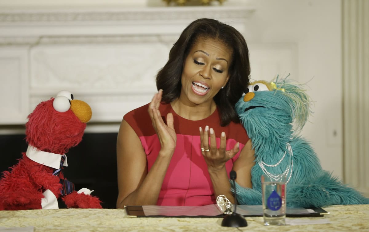 First lady Michelle Obama joins with &quot;Sesame Street&quot; characters Elmo, left, and Rosita to help promote fresh fruit and vegetable consumption to kids in an event Wednesday in the State Dining Room of the White House in Washington, D.C.