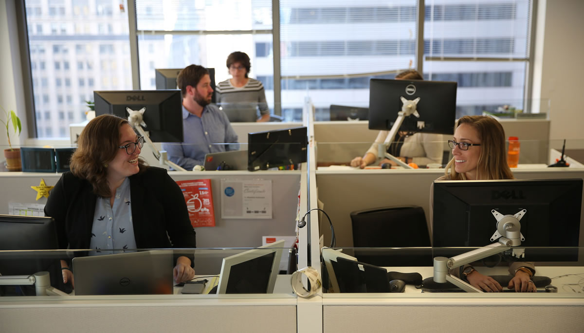 Madeline Hasbrouck, left, and Lauren Crawford, right, and other employees at Vitality Group work in their new office, with smaller desks and standing options Nov. 3 in Chicago.