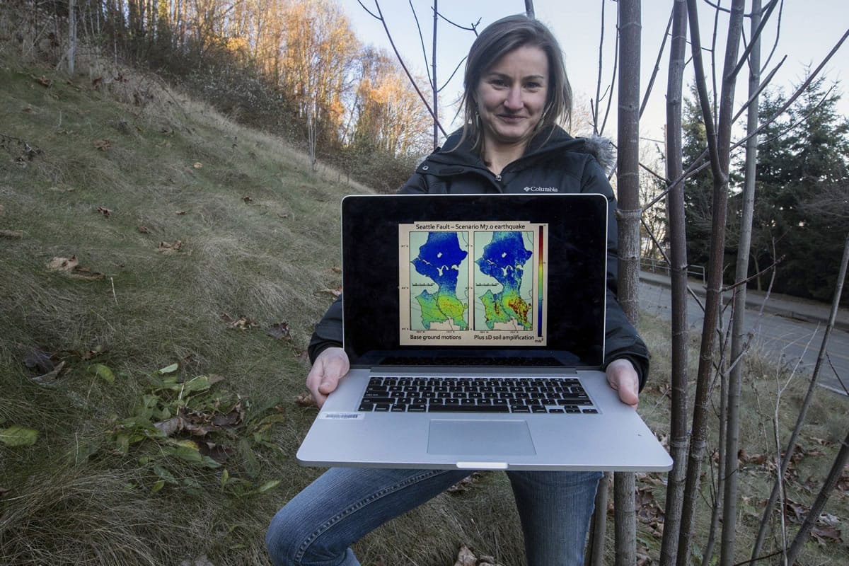 Kate Allstadt, lead author of a new report on landlides, stands on a West Seattle slope with one of the programs she uses to predict slides triggered by earthquakes.