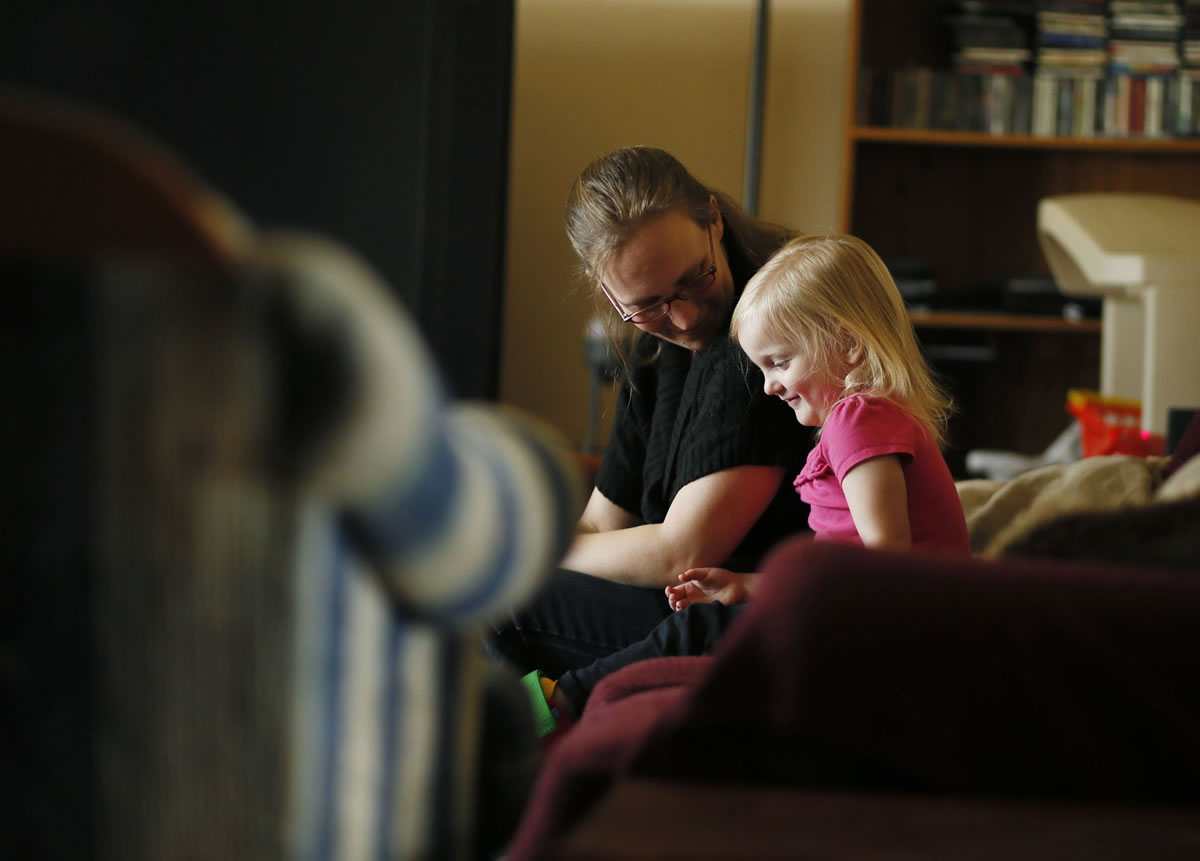 Angie Derry, left, sits with her 3 year-old daughter, CJ Mershon-Derry, on Dec. 5 at their home in Machesney Park, Ill.