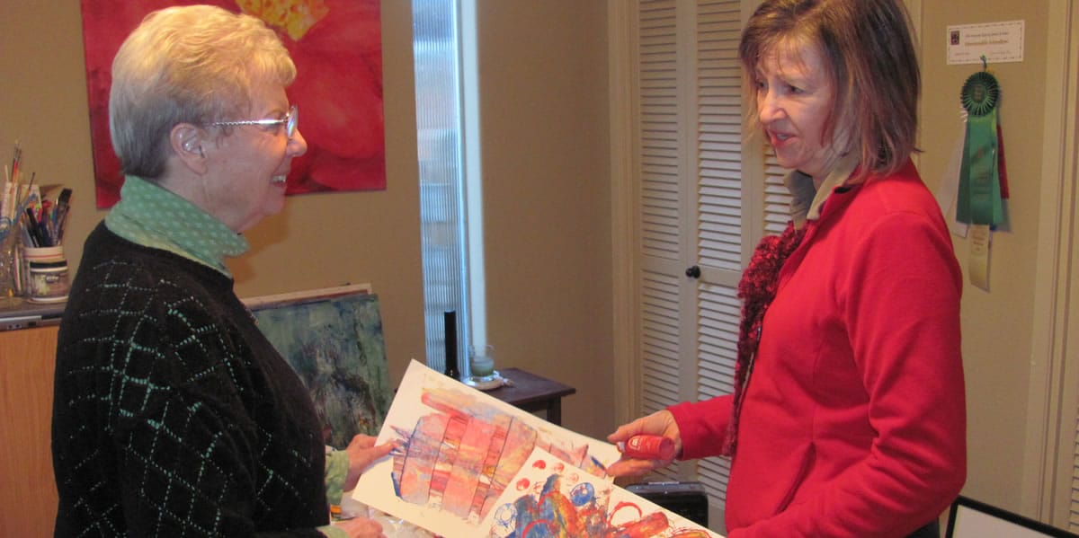 Fellow artists and friends Katey Sandy (left) and Judith Howard reminisce about a children's art project they collaborated on prior to retirement.