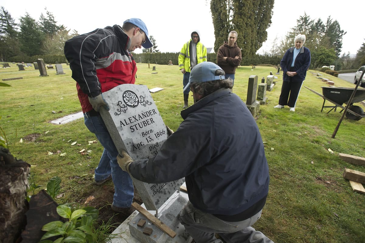 Joey Fuerstenberg, left, and Kyle Cochran of Vancouver Granite Works replace a grave marker for Alexander Stuber at the Camas Cemetery.