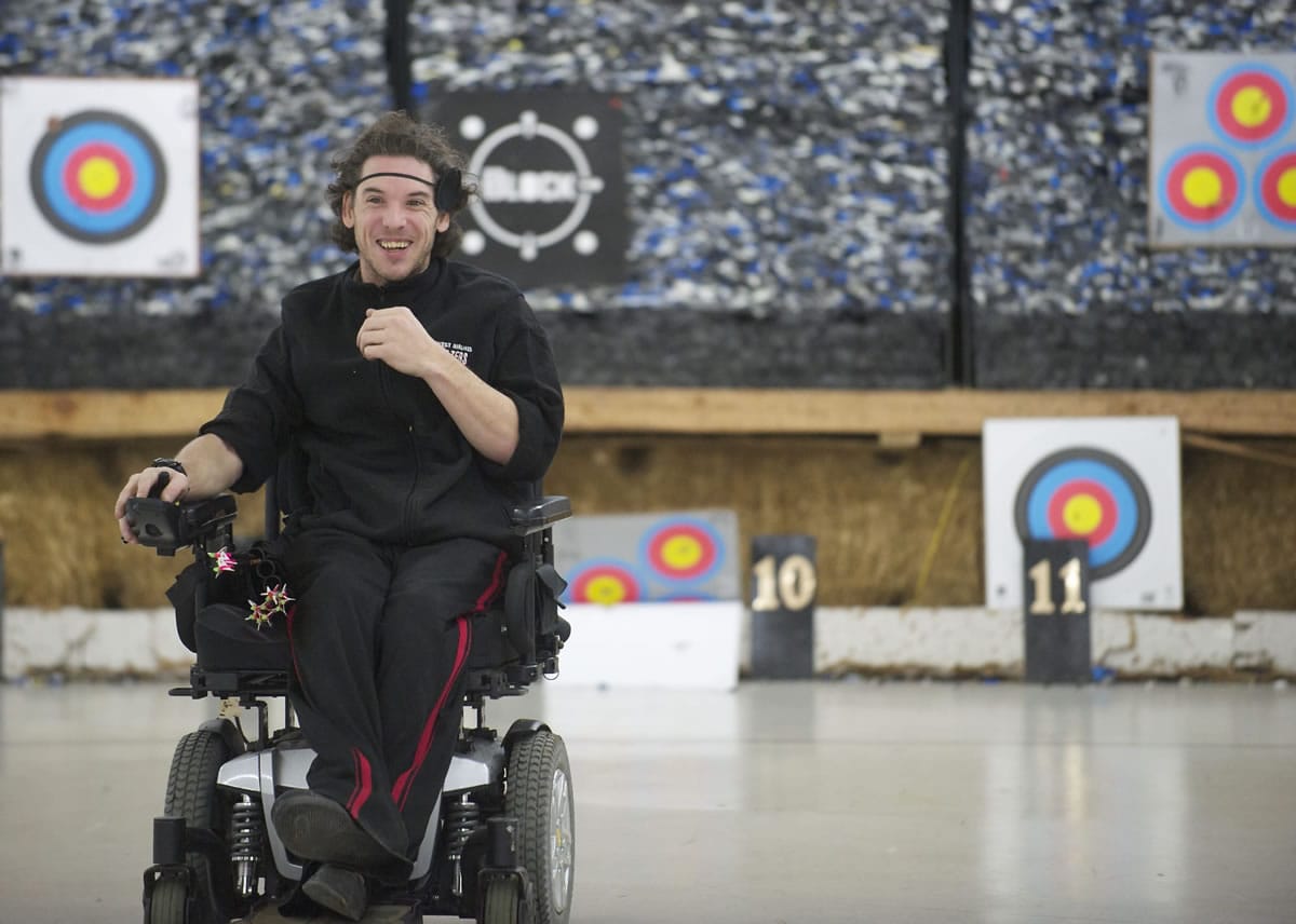 Chris Cash, who uses a wheelchair due to cerebral palsy, heads to the firing line after setting his target at Archery World, where he volunteers regularly.