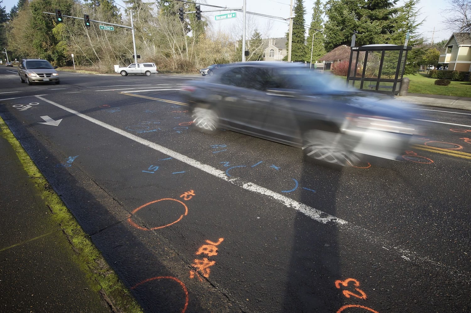 Motorists drive over police markings at the intersection of Northeast 72nd Avenue and Vancouver Mall Drive, where two people were struck and killed by a hit-and-run driver Sunday evening.