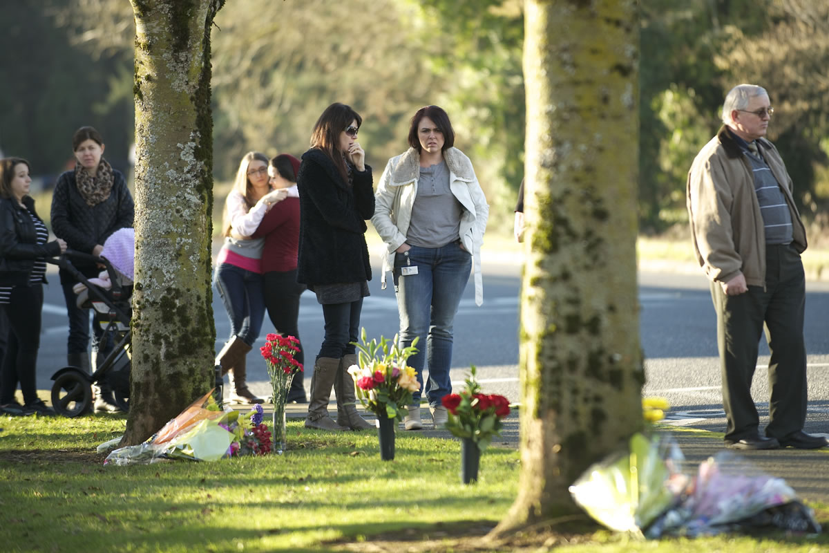 A group of people stop to pay their respects Monday afternoon at the site of a hit-and-run crash that killed two women Sunday night at the intersection of Northeast 72nd Avenue and Northeast Vancouver Mall Drive.