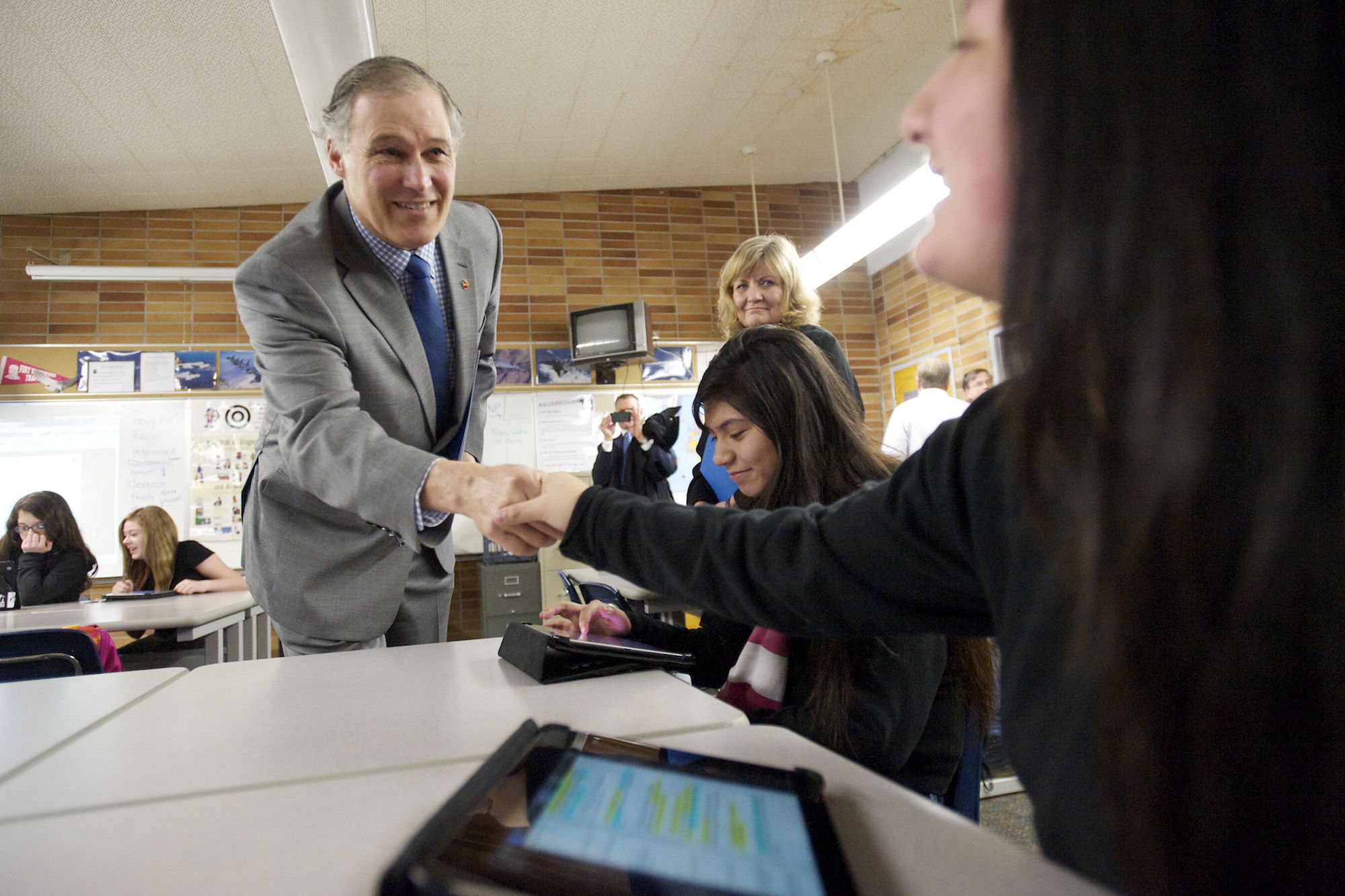 Gov. Jay Inslee, left, and his wife, Trudi, greet McLoughlin Middle School students Lizbeth Martinez, seated at center, and Karol Hoyos, both 14, in Bill Sixour's U.S. history class on Wednesday. They were using tablets to learn about the Underground Railroad.