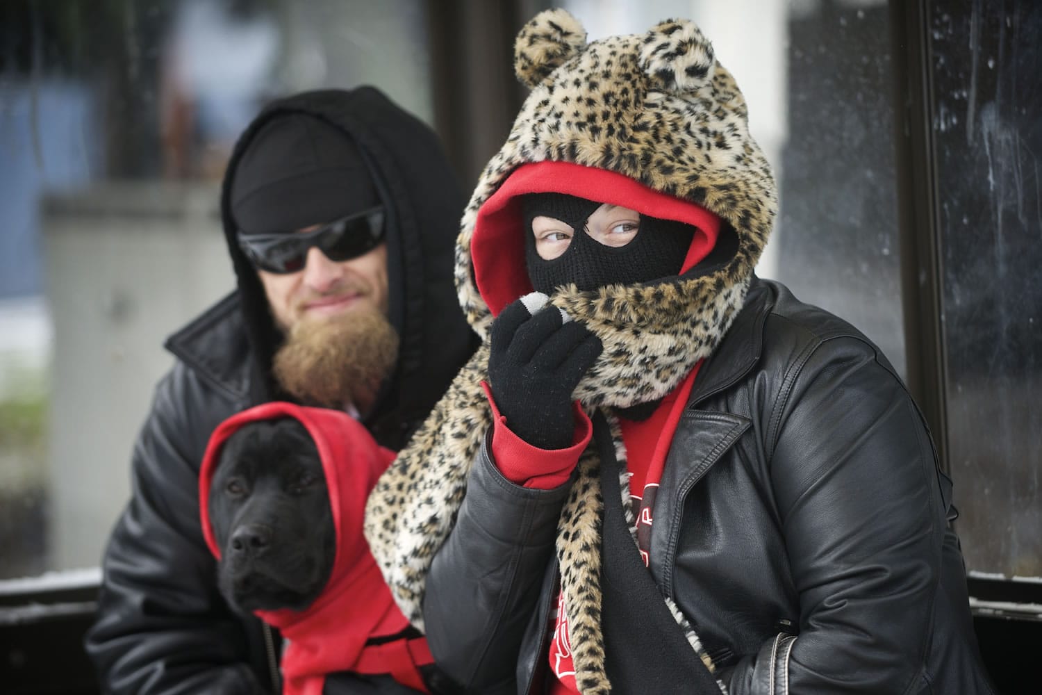 Trisha Pogue, right, covers her face from below-freezing temperatures while waiting for a bus with Joshua Romine and their dog, Leah, in Vancouver on Friday.