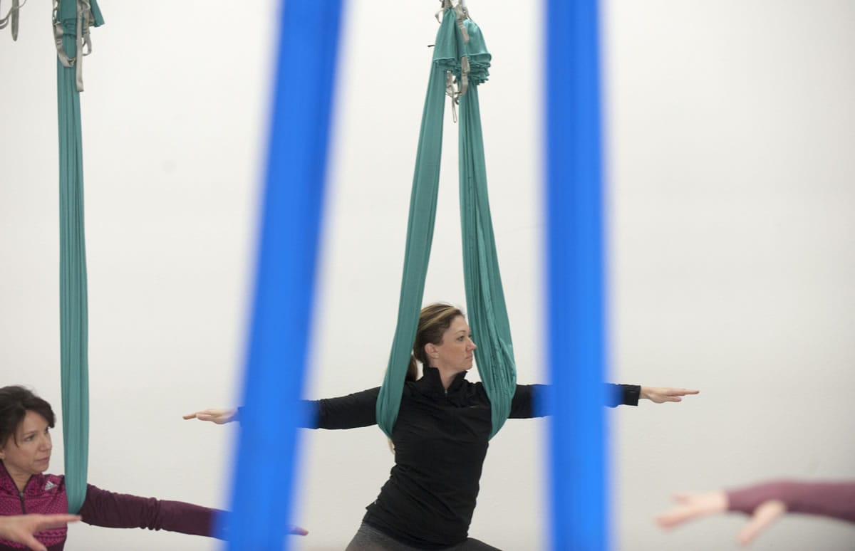 Crystal Hoss stretches with the aid of a silk hammock during an aerial yoga class Wednesday at Virtuosity Performing Arts Studio in downtown Camas.