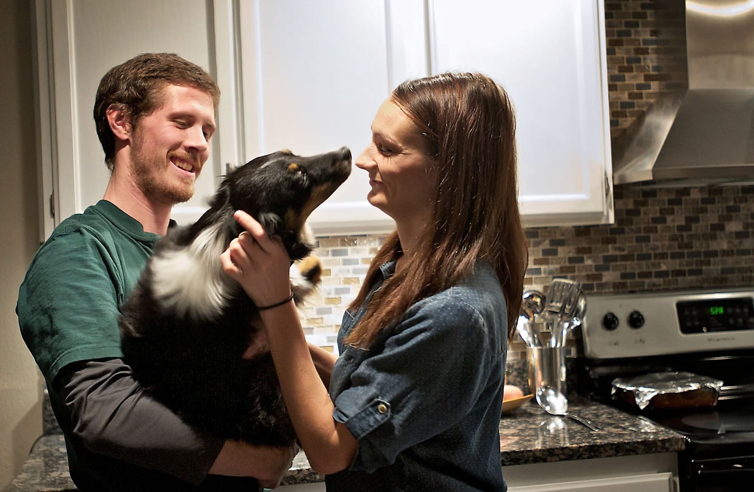 Lindsey and Jesse McChesney pet their dog, Dottie, inside their Vancouver home Friday. The McChesneys currently have an individual health insurance plan through Kaiser Permanente.