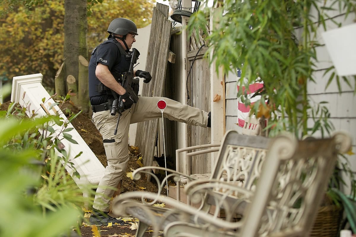 Vancouver police Detective Adam Ruth kicks in a fence during a raid on a chronic problem house in the Hough neighborhood.