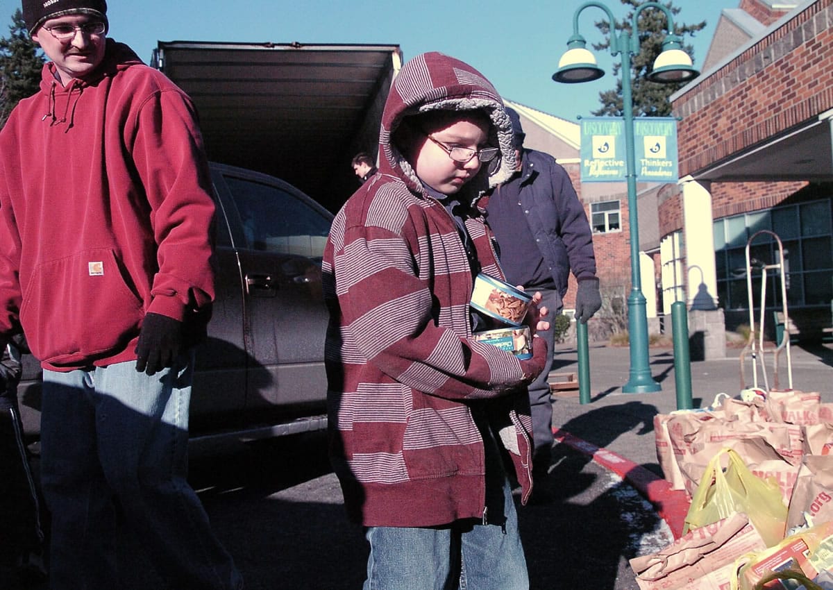 Seth Delory, 7, helps his dad, Steve Delory, left, deliver food to the Walk &amp; Knock at Discovery Middle School.