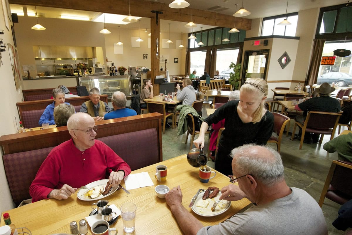 Jenny George pours coffee for Jim Massey, lower right, as he eats breakfast with Vic Townsend at Dulin's Village Cafe in downtown Vancouver on Tuesday.