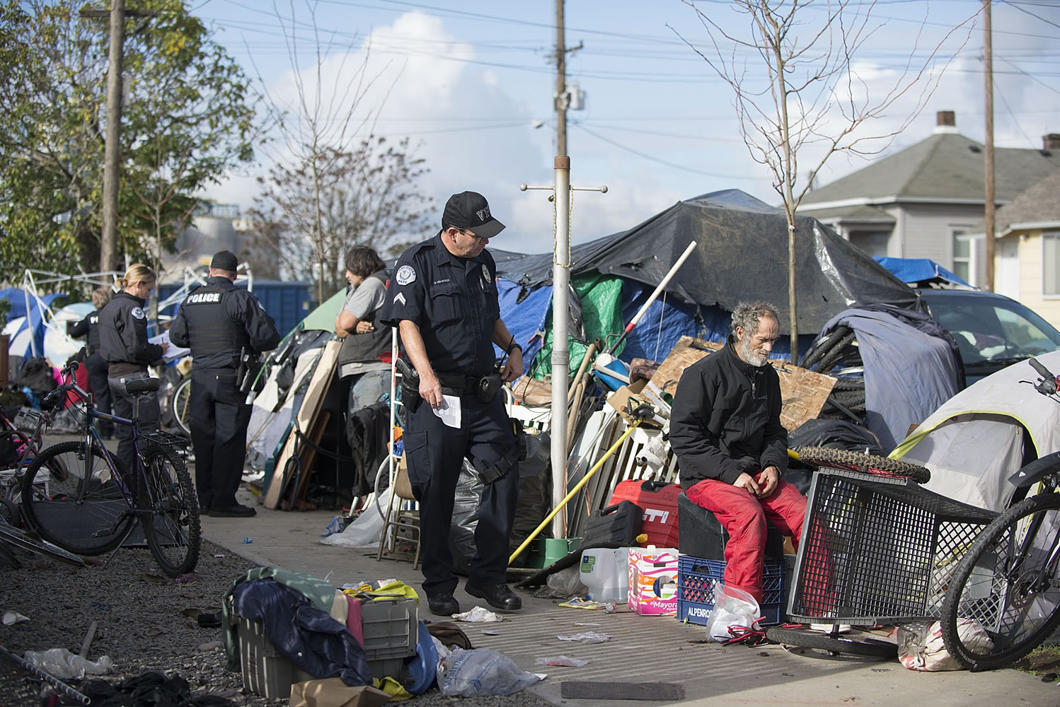 Police Cpl. Stuart Hemstock, center, and other officers work with homeless people Monday morning as they seek to enforce the city's camping law.