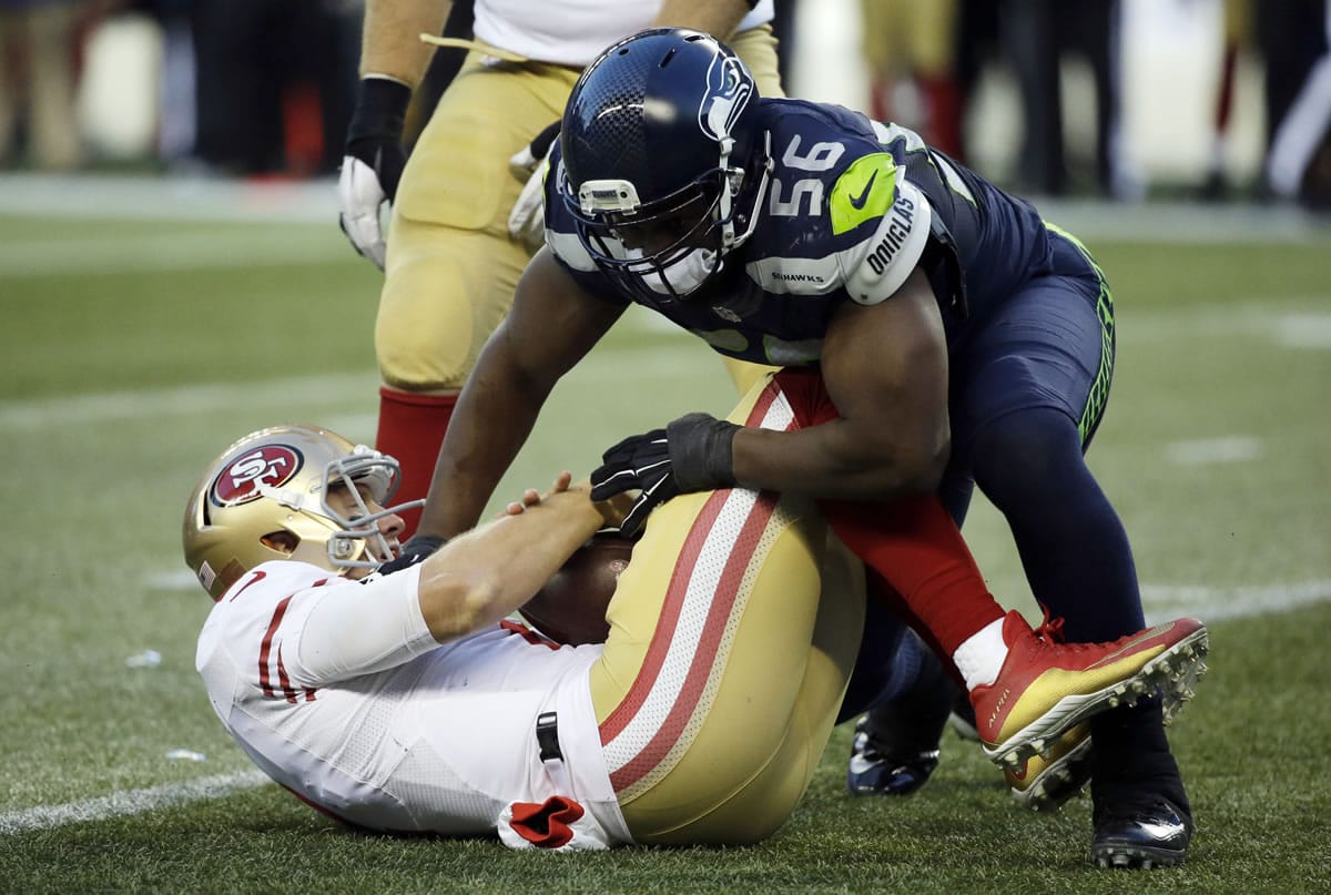 Seattle Seahawks defensive end Cliff Avril, right, sacks San Francisco 49ers quarterback Blaine Gabbert, left, in the second half of an NFL football game, Sunday, Nov. 22, 2015, in Seattle.