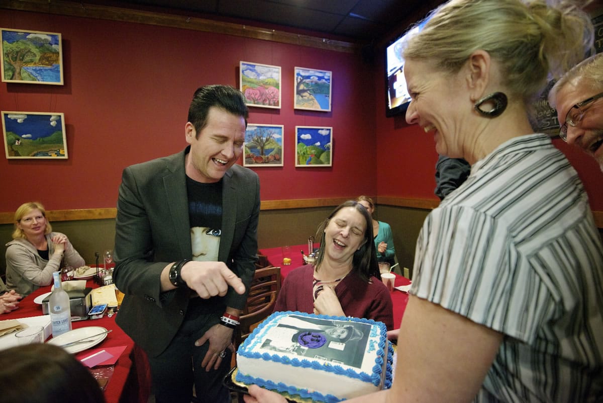Seth Aaron Henderson laughs at a photograph of himself on a cake presented to him by Karen McMillen and Cliff McMillen, right, owners of Vancouver Pizza, at the restaurant Thursday.