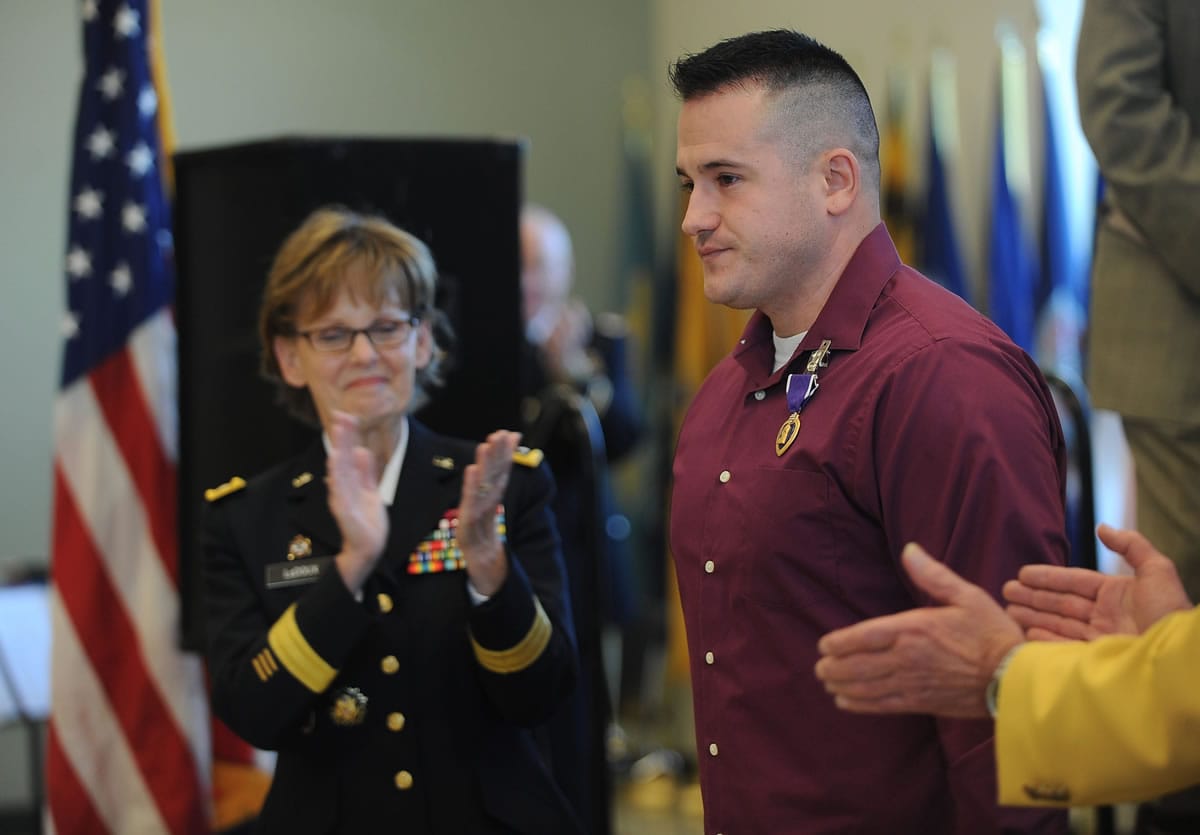 Maj. Gen. Karen LeDoux, left, leads the applause for Arty Feldman after formally presenting a Purple Heart medal to the Vancouver veteran Wednesday at the Armed Forces Reserve Center.