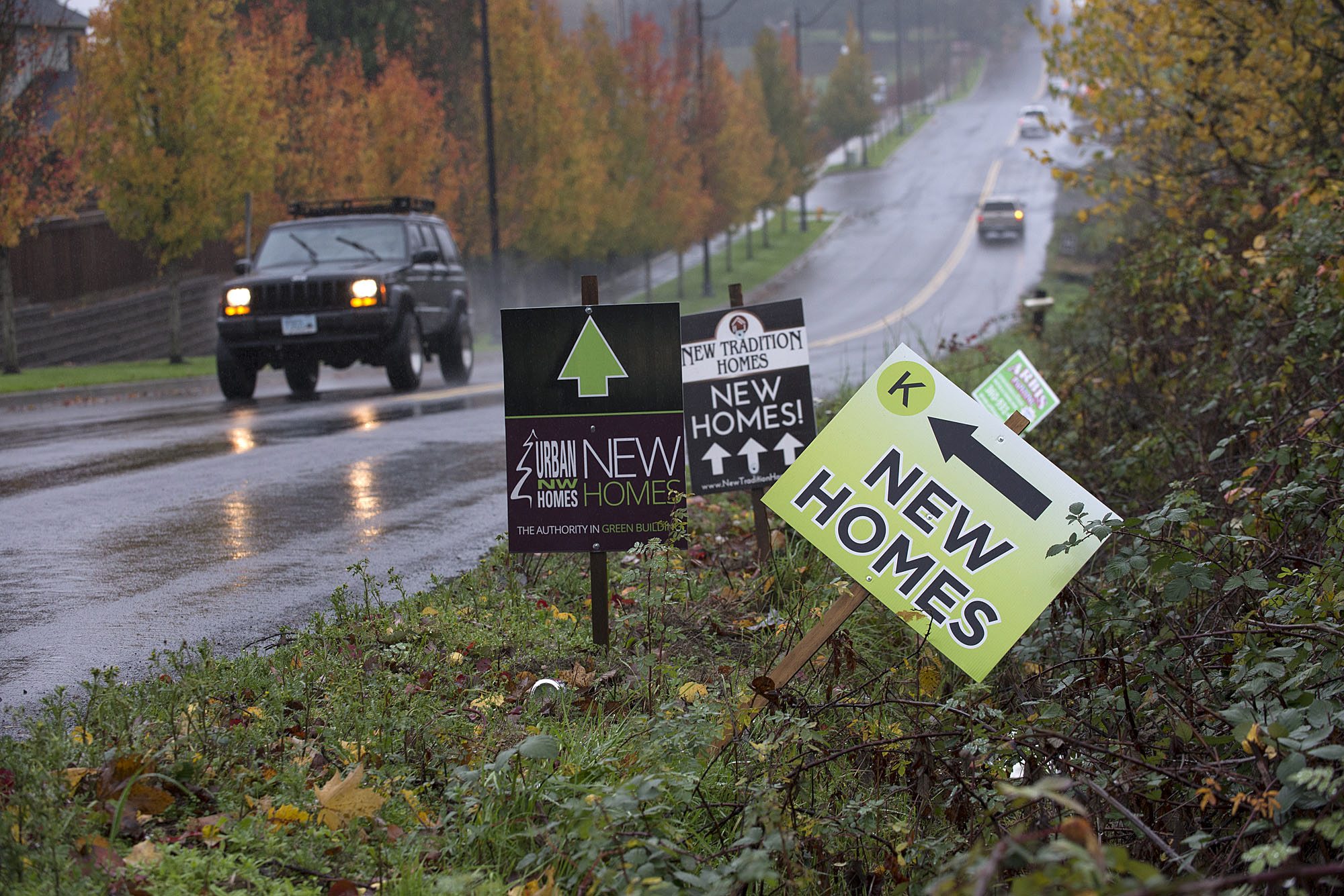 A motorist driving on North 45th Avenue passes signs advertising new houses for sale on Nov. 19 in Ridgefield.
