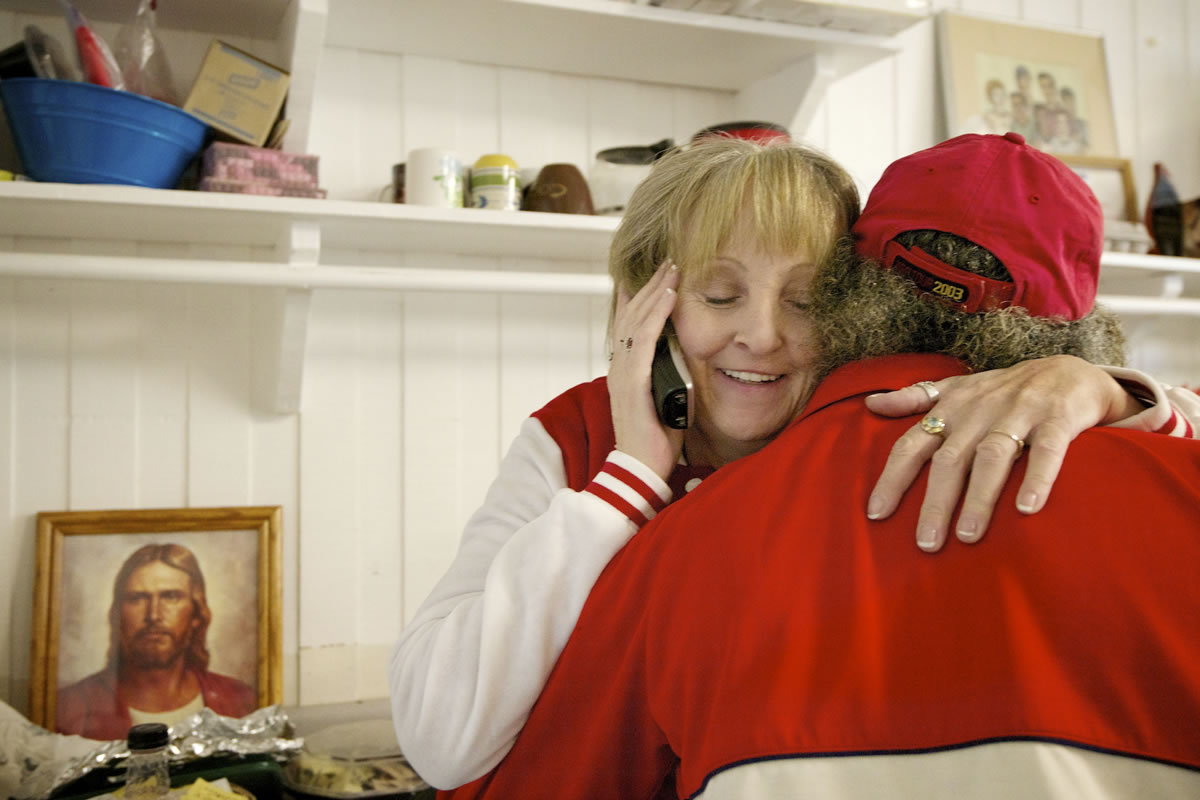 Multitasking hostess Michele Kruchoski takes a phone call while welcoming fellow volunteer Albert Fletcher to Martha's Pantry, a food pantry and community center for people with HIV/AIDS.