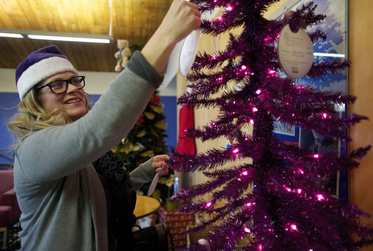 Home Instead Senior Care President Julie Williams hangs paper ornaments on a small Christmas tree Wednesday at the Marshall Center, which list modest gifts for seniors in need and gives the public a chance to play Santa Claus.