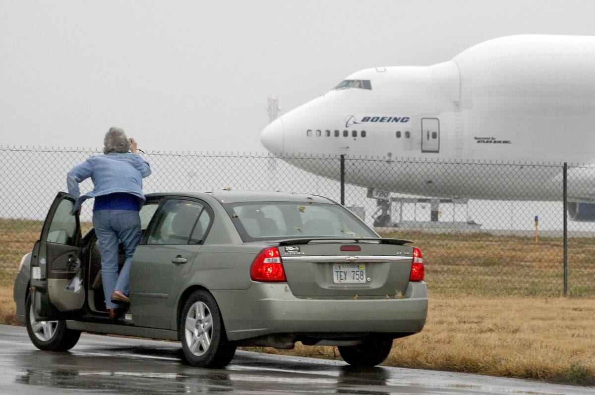 A woman tries to take a photo of a Boeing 747 Dreamlifter on Thursday that mistakenly landed at Col. James Jabara Airport in Wichita, Kan.