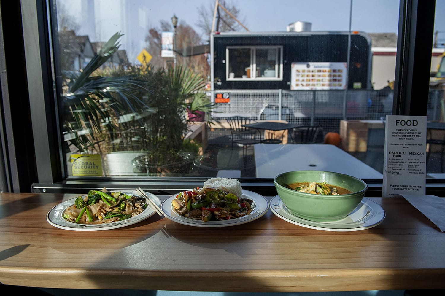 Pad See Ew, from left, Pad Phet and Evil Prince from the E-San Thai food cart visible through the window sit on the counter at Trap Door Brewing on Friday afternoon, Nov. 20, 2015, in Vancouver.