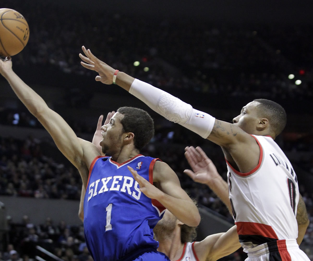 Philadelphia 76ers guard Michael Carter-Williams, left, goes to the hoop against Portland Trails Blazers guard Damian Lillard during the first half of an NBA basketball game in Portland, Ore., Saturday, Jan. 4, 2014.