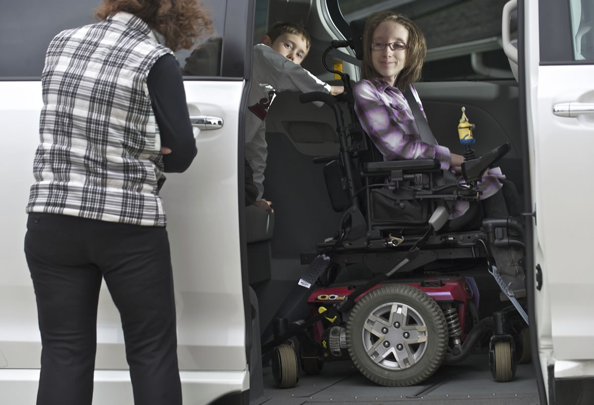 Daniel Benson, 7, center, helps sister Emily, 12, show the ease of using the family's new wheelchair-accessible minivan.