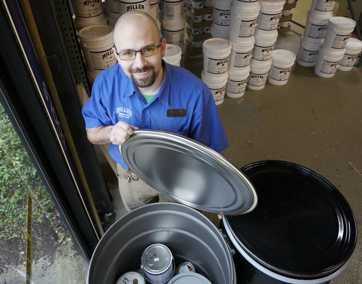 Tim Albright, a salesperson for the Orchards Miller Paint store, uncovers a container partially filled with recycled paint.