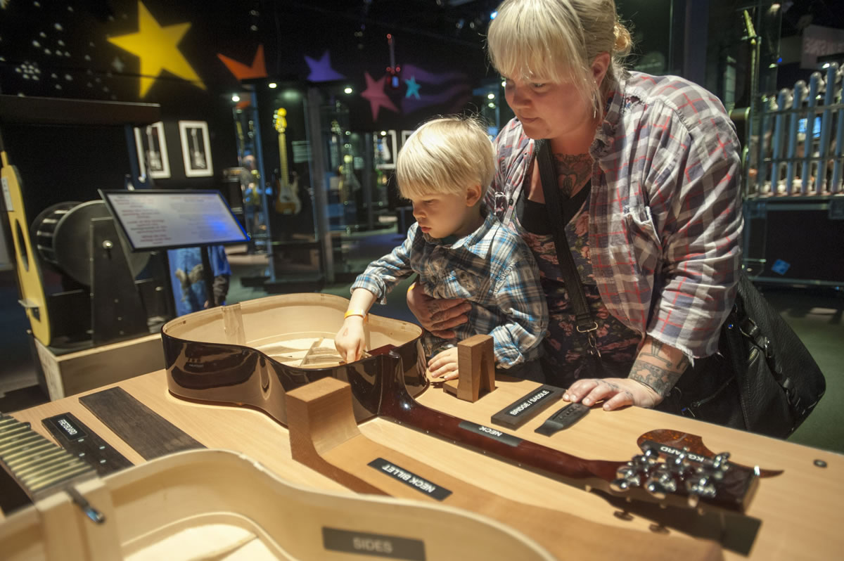 Nanny Summer Michaud-Skog checks out the guts of an acoustic guitar with her charge, 3-year-old Andrew, during a visit to &quot;Guitar: The Instrument that Rocked the World!&quot; at the Oregon Museum of Science and Industry.