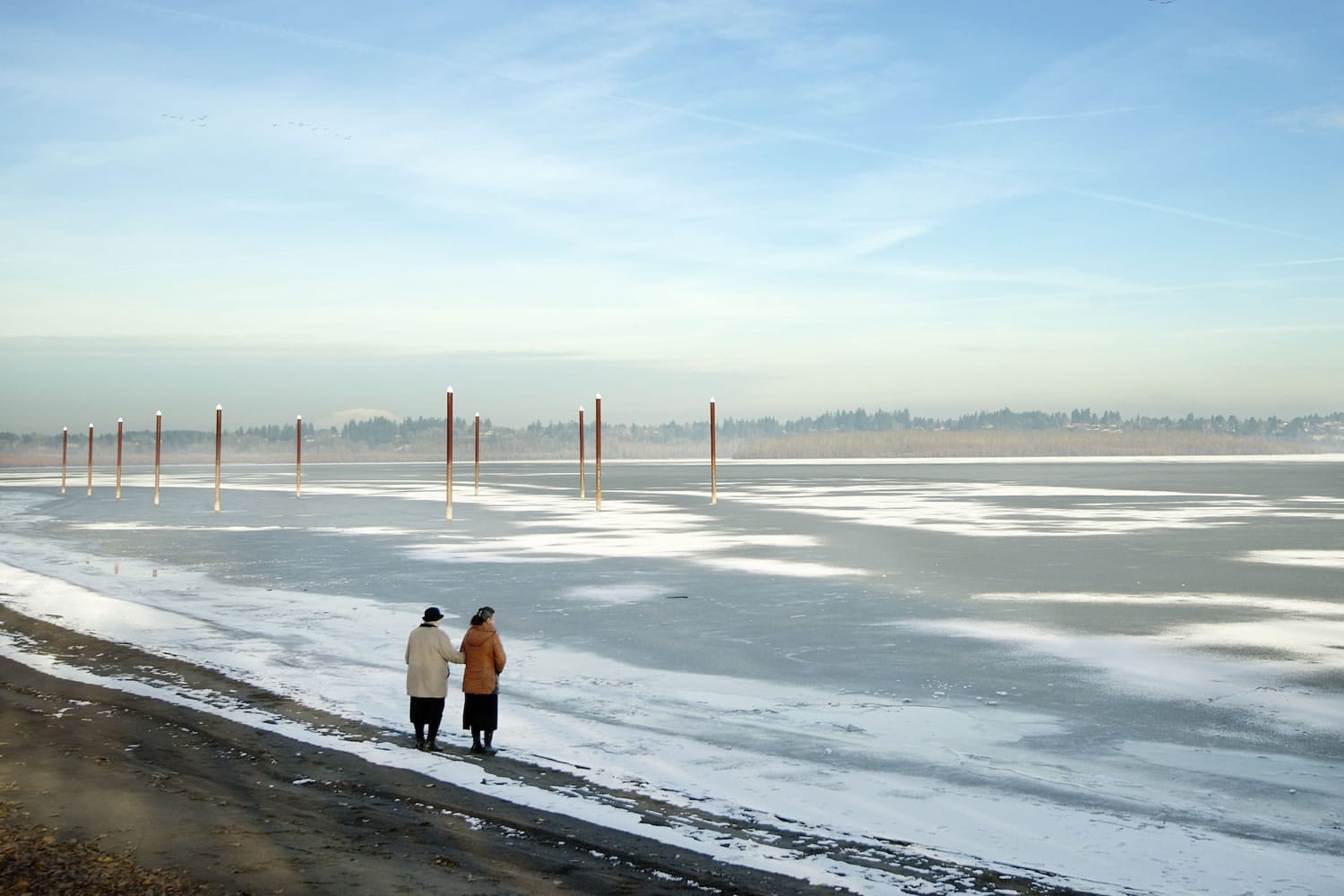 A pair of women stop at the edge of Vancouver Lake to take photos and look at the ice and snow Wednesday.
