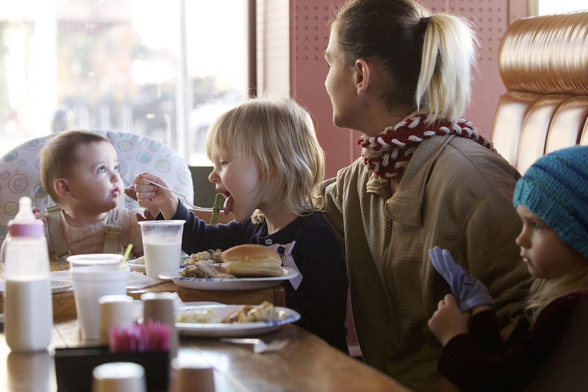 Melissa Murdock, 26, and three of her daughters, from left, Angel Raptopoulos-Hair, 8 months, Julie Walker, 3, and Rayne Walker, 4, enjoy being together at Chronis' Restaurant and Lounge during the annual free Thanksgiving meal.