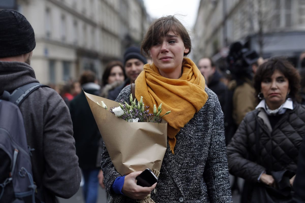 A woman carrying flowers cries in front of the Carillon cafe and the Petit Cambodge restaurant in Paris Saturday Nov. 14, 2015, a day after over 120 people were killed in a series of attacks in Paris. French President Francois Hollande said at least 127 people died Friday night when at least eight attackers launched gun attacks at Paris cafes, detonated suicide bombs near France's national stadium and killed hostages inside a concert hall during a rock show.