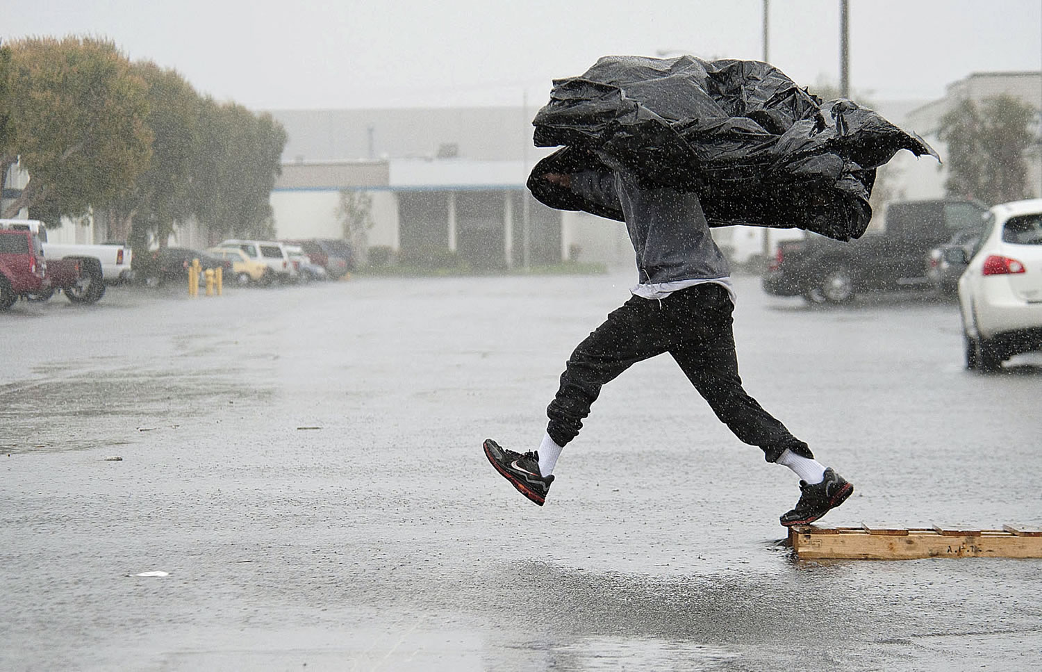 Assembly worker Terry Young, 24, of Rialto, Calif., uses a sheet of plastic to protect himself from a downpour Friday in Anaheim, Calif.
