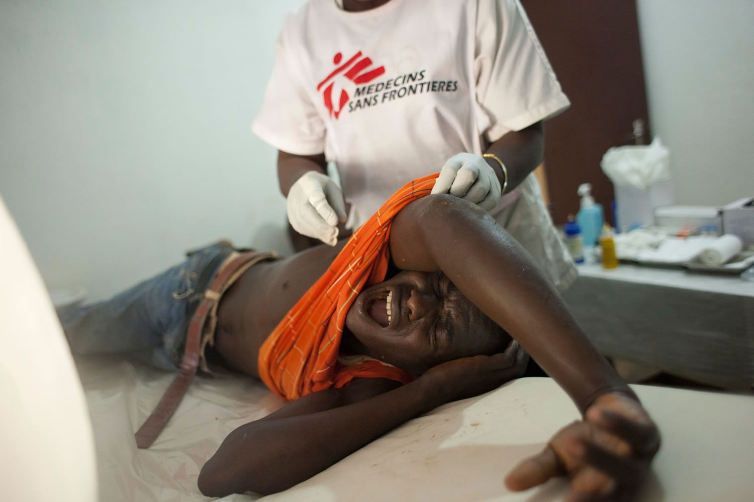 A young man who was hit in the back by a stray bullet on Christmas Eve cries out in pain as he receives medical care Wednesday at a Doctors Without Borders clinic in Bangui, Central African Republic.