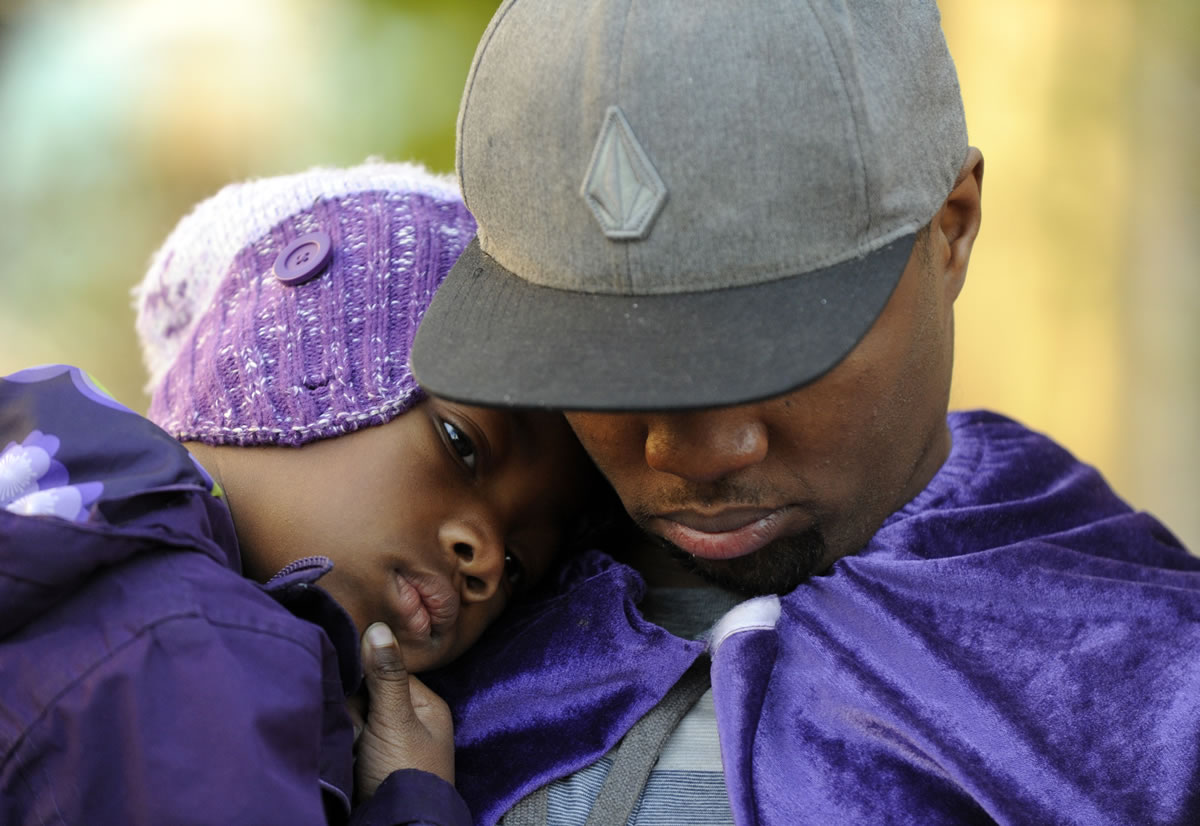 Quinton Reynolds, of Emeryville, wears a purple cape as he holds his daughter, Qniyah Reynolds, 4, as he gathers with others outside of Children's Hospital Oakland in support of Jahi McMath in Oakland, Calif., on Monday.