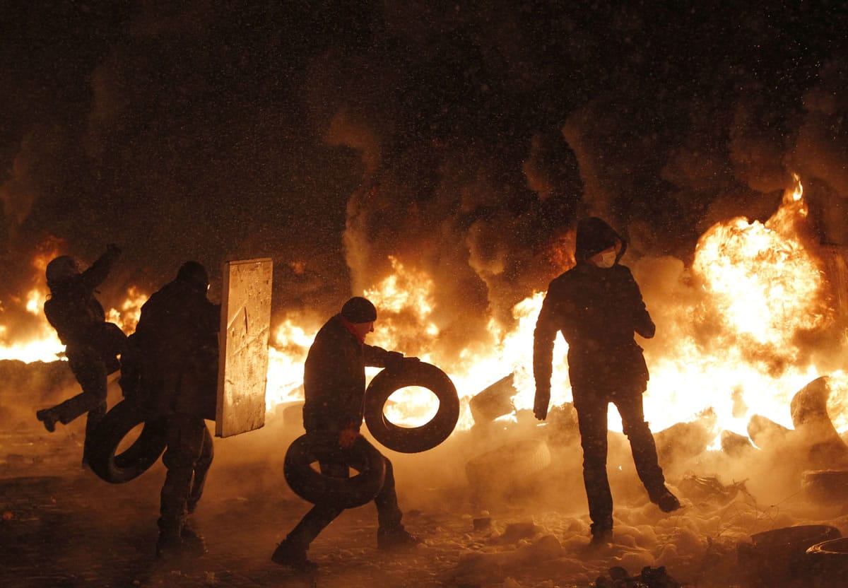 Protesters throw tires onto a fire during clashes with police in central Kiev, Ukraine, on Wednesday.
