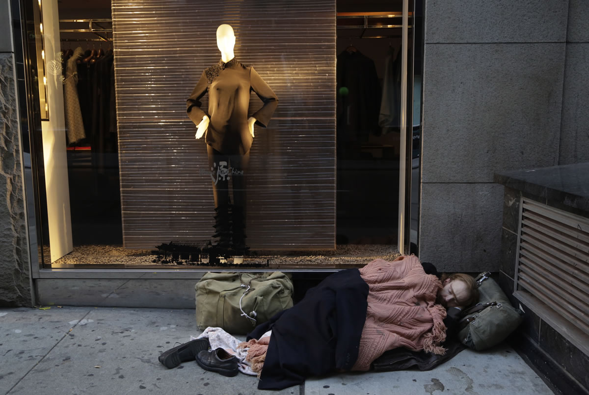 A man sleeps on the sidewalk under a holiday window last year at Blanc de Chine clothing store in New York.