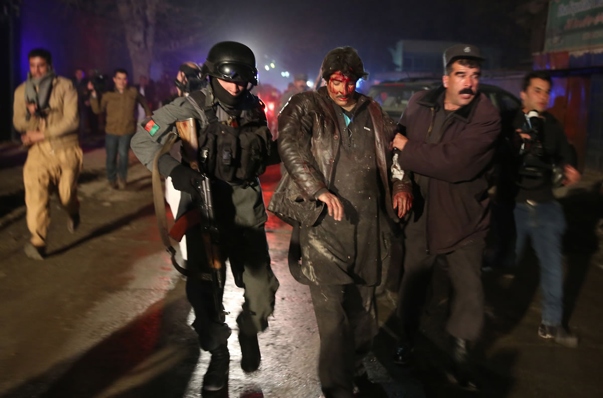 Afghan police forces assist an injured man at the site of an explosion Friday in Kabul, Afghanistan.