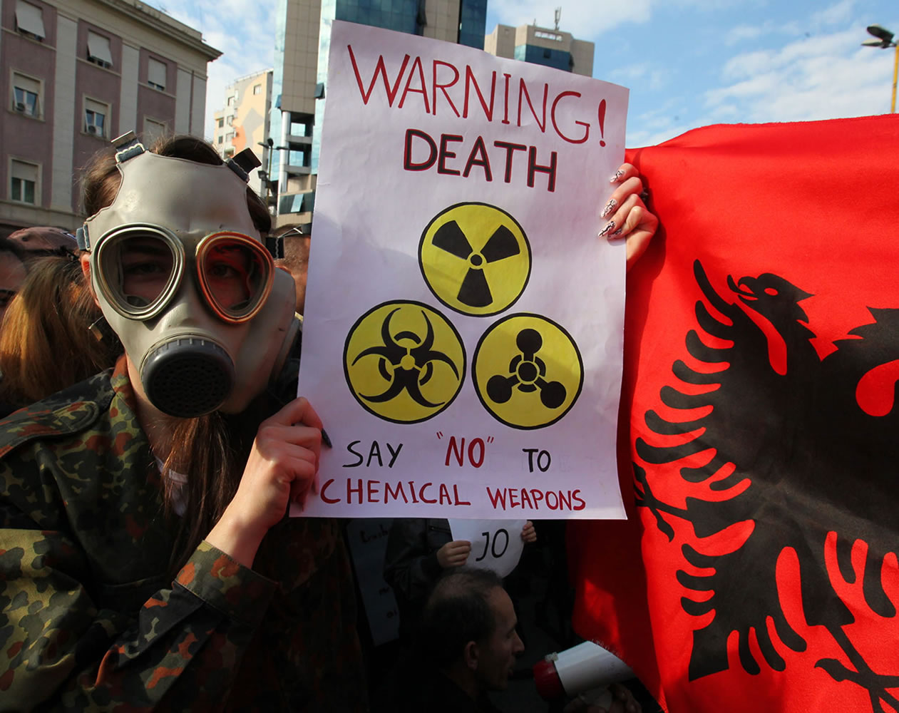 An Albanian student wears a gas mask and holds a sign during a protest against chemical weapons during a protest against the dismantling of Syrian chemical weapons in Albania in front of the Prime Minister's office in Tirana on Nov.
