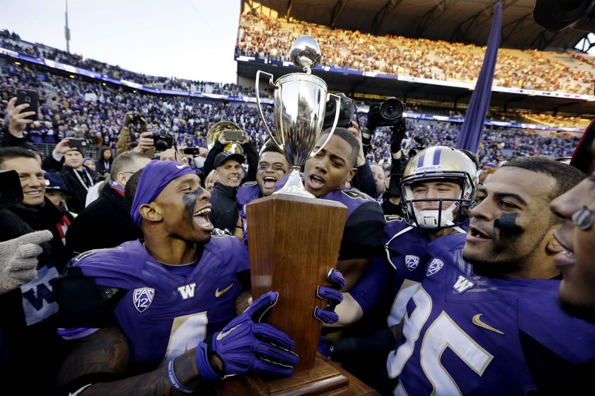 Washington players, including Jaydon Mickens, left, and Brian Clay, center, cheer as they hold the Apple Cup trophy after the team beat Washington State in an NCAA college football game Friday, Nov. 27, 2015, in Seattle. Washington won the annual Apple Cup game, 45-10.