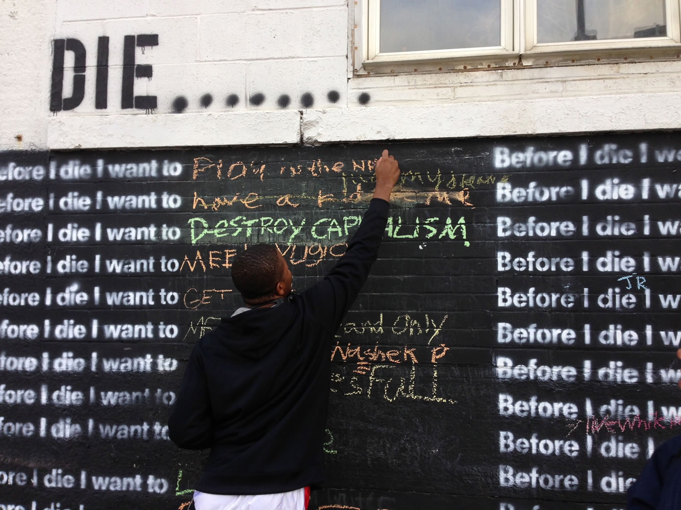 Nyquis Turner, 16, writes &quot;Play in the NFL&quot; on a wall in Syracuse, N.Y., that invites passers-by to complete the sentence: &quot;Before I die, I want to...&quot;  The global phenomenon started in 2011, when artist Candy Chang created the first wall on an abandoned house in her New Orleans neighborhood.